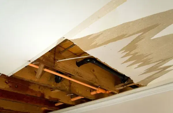 Water-stained ceiling drywall cut open to the joists after a leak in Brooksville