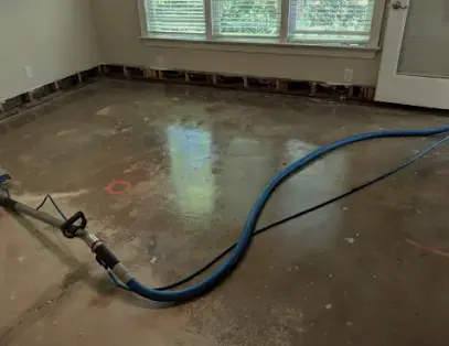Extraction hose pulling water off a wet concrete floor in a Brooksville home